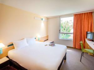 里沃萨尔特ibis Perpignan Nord Rivesaltes的酒店客房设有一张白色大床和一个窗户。