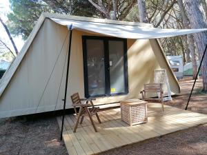 阿尔比尼娅Camping Village Oasi的木制甲板上的帐篷,配有桌椅