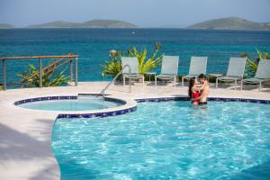 圣约翰噶罗斯柏银特度假酒店的坐在海洋旁游泳池里的女人