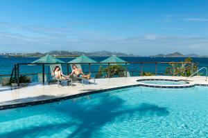 圣约翰噶罗斯柏银特度假酒店的两个女人坐在游泳池旁的椅子上