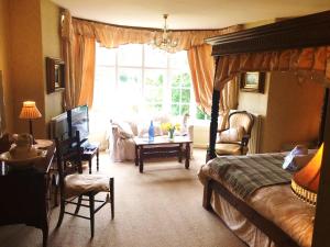 康威Glyn Isa Country House B&B and self catering Lodge的一间卧室配有一张床、一张桌子和一个窗户。