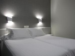 桑亨霍Hotel Ton的一张白色的床,上面有两个枕头和两个灯