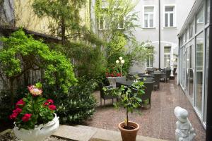 普劳恩亚历山大酒店的庭院设有桌椅和植物花卉