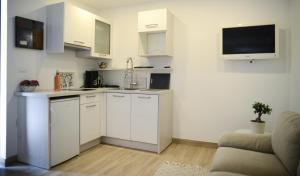罗维尼Modern getaway Studio for two的一间厨房,配有白色橱柜和墙上的电视