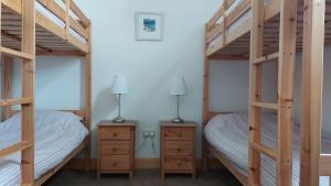 赫姆斯代尔Helmsdale Lodge Hostel - all rooms en-suite的一间卧室设有两张双层床和两盏灯。