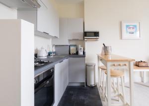 赖德Serene in Ryde的厨房配有白色橱柜和木桌