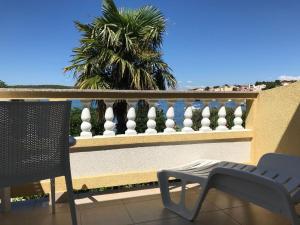 巴尔巴特纳拉布Apartments and Rooms Villa Luci的阳台配有椅子、围栏和棕榈树。