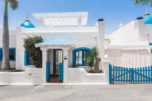 科拉雷侯Bahiazul Villas Corralejo by Vreagestion的白色的房子,有蓝色的大门和棕榈树