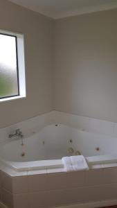 哈韦拉都铎汽车旅馆的白色的浴室设有浴缸和窗户。