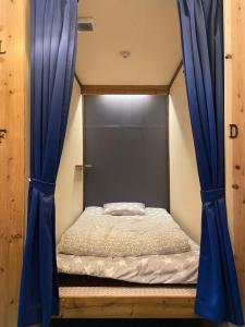 大阪Hostel Furoya的蓝色窗帘的房间的一张床位