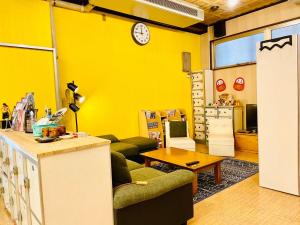 大阪Hostel Furoya的客厅设有黄色墙壁和时钟