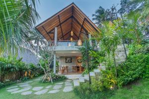 乌布Lasamana Villas Ubud by Pramana Villas的花园中带木屋顶的房子