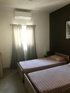 卢加Luqa Apartment - 5 mins from Airport的一间卧室设有两张床,窗户配有窗帘