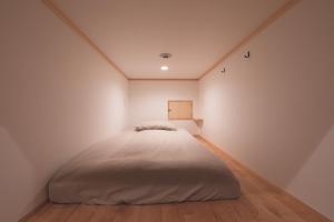 伊势市THY GUEST HOUSE的白色墙壁和木地板的客房内的一张床位