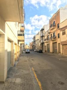 卢加Luqa Apartment - 5 mins from Airport的一条空荡荡的街道,有建筑和一辆汽车停在路边