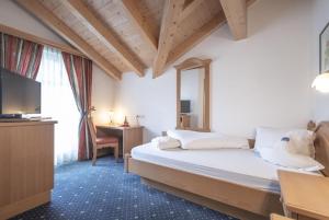 卢塔戈施奈德加尼酒店的一间卧室配有一张床、一张书桌和一台电视