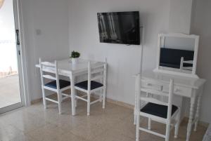 普罗塔拉斯佛斯霍斯海滩公寓 的白色的桌子和椅子以及客房内的电视