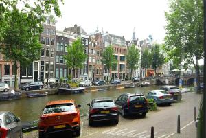 阿姆斯特丹Stuart Luxury Rooms的一群停在河边的汽车,有建筑物