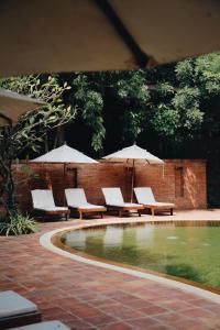 Prakhon ChaiHotel de l'amour SHA PLUS的一个带椅子和遮阳伞的庭院和一个游泳池