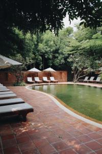 Prakhon ChaiHotel de l'amour SHA PLUS的庭院内带椅子和遮阳伞的游泳池