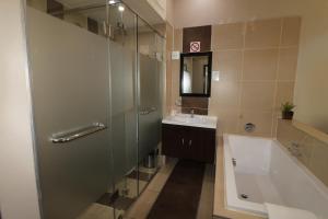 约翰内斯堡Alcazaba Lodges的带淋浴、盥洗盆和浴缸的浴室
