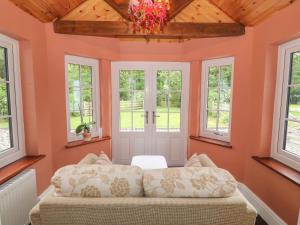 登比Bawbee Cottage的一间卧室设有橙色的墙壁、窗户和沙发