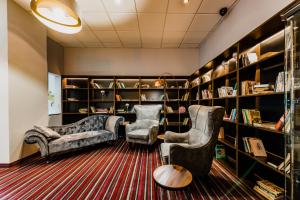 塔博尔派勒萨特酒店的图书馆配有两把椅子、一张沙发和书架