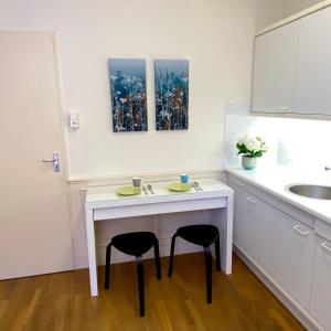 斯海弗宁恩Basic Little House Scheveningen的厨房配有一张白色的桌子和两张凳子
