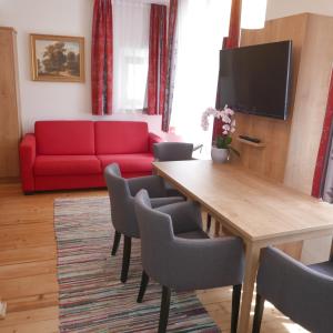 哈莱恩Appartement Katharina 2 Personen Hallein bei Salzburg的客厅配有红色的沙发、桌子和椅子