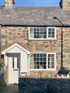 康威Gorlan Cottage Tal y Bont Conwy的石屋,设有白色门和两扇窗户