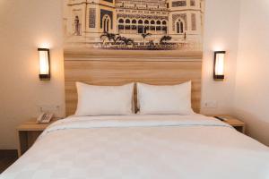 棉兰Cordela Inn Millennium Medan的一间卧室配有一张带两盏灯的大型白色床。