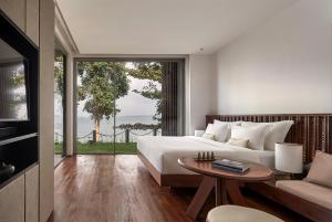 Phumĭ Kaôh RœsseiKoh Russey Resort的一间卧室配有一张床、一张桌子和一张沙发