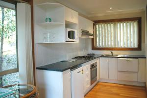 Bewong贝翁江湾别墅的厨房配有白色橱柜、水槽和微波炉