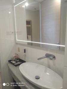 雅加达Grand G7 Hotel Kemayoran的浴室设有白色水槽和镜子