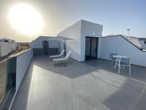 塞博河畔卡莱塔La Pardela Exclusive Apartamentos的屋顶上带桌椅的阳台