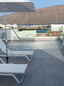 塞博河畔卡莱塔La Pardela Exclusive Apartamentos的一个带遮阳伞和椅子的庭院和一个游泳池