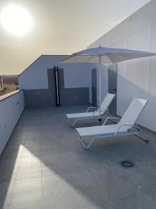 塞博河畔卡莱塔La Pardela Exclusive Apartamentos的大楼内提供2把躺椅和1把遮阳伞