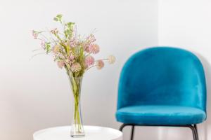 希贝尼克Globo - self check-in hostel的蓝色椅子旁边的桌子上花瓶