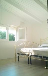托雷拉皮罗Dimora Arnesano的白色的客房设有一张床和两个窗户。