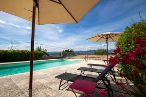 阿普特Chez Manon的一个带两把椅子和一把遮阳伞的庭院和一个游泳池