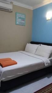 PakaManja Inn, Paka的一间卧室配有一张带白色床单和橙色毯子的床。