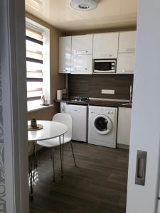哈尔科夫Сдам посуточно однакомнатную квартиру的厨房配有白色橱柜、桌子和洗衣机