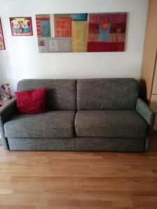 瓦勒斯Appartamento MaVi的一张灰色沙发,上面有红色枕头,坐在画底下