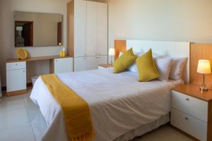 马普托Triunfo Guest House的卧室配有一张带黄色枕头的大型白色床。