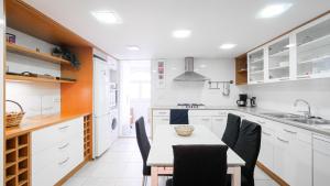 巴塞罗那Bed&BCN Gracia III的厨房配有白色橱柜和桌椅
