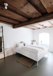 林茨CHARMANTES APARTMENT im Herzen von Linz的白色卧室设有一张白色大床和木制天花板