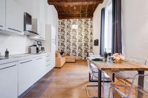 罗马Klioos Apartment的厨房配有白色橱柜和木桌