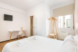马翁Hostal Jume - Urban Rooms的白色卧室配有白色的床和书桌
