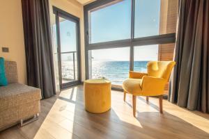古泽尔坎里MAIA Luxury Beach Hotel & Spa的客厅设有黄色椅子和大窗户