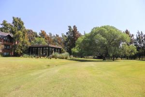 皮拉尔La Posta del Pilar Hotel & Spa的一座带房子和绿色庭院的高尔夫球场